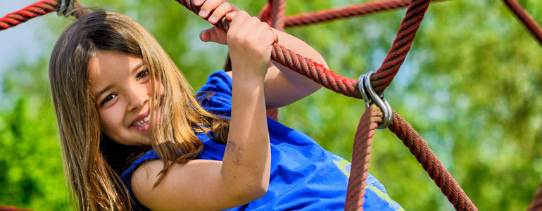 Girl in blue t-shirt palying in a playgound at a park